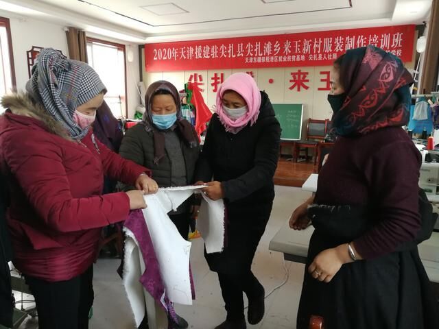 2020年12月11日，来玉村扶贫车间里几位村民正拿着一件藏服半成品研究制作工艺。（新华社记者顾玲摄）