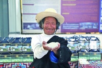 △阿里地区革吉县盐湖乡粗盐巴加工厂，75岁的布玛尔捧起新盐，笑得灿烂。图片为本报记者刘宇航摄/光明图片