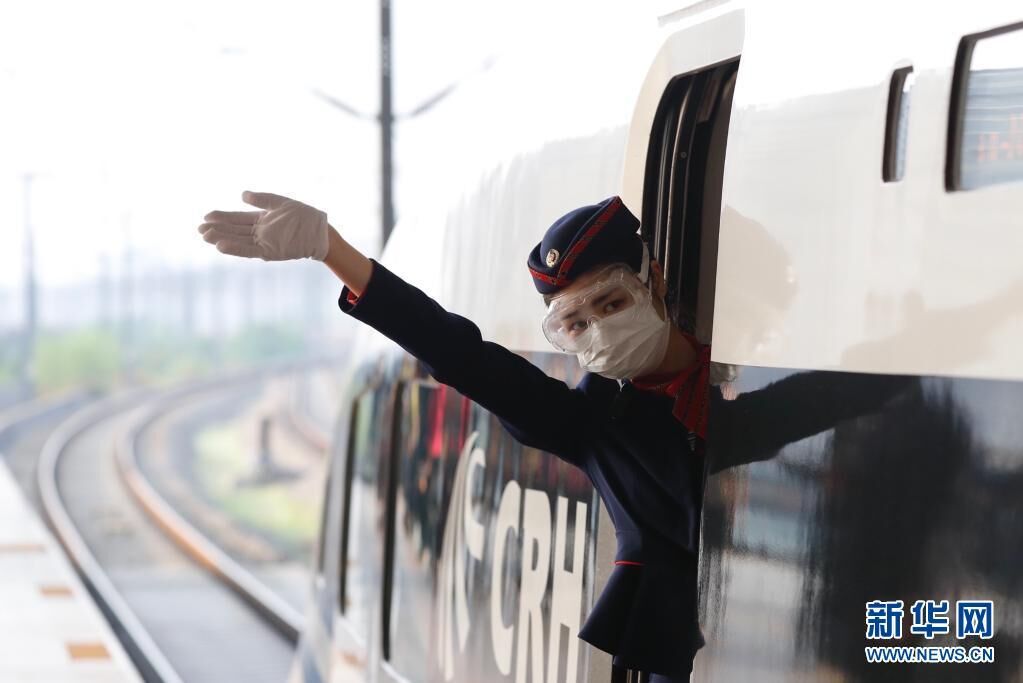 在武汉站，G431次列车乘务员艾婷婷在发车前向乘客挥手（2020年4月8日摄）。这是武汉市正式解除离汉离鄂通道管控措施后开往湖北省外的首趟始发列车。新华社记者 沈伯韩 摄