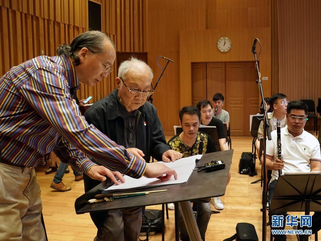 6月9日，吕其明（左二）在上海爱乐乐团录制管乐版《红旗颂》的现场，与指挥林友声讨论乐谱。新华社记者 刘颖 摄