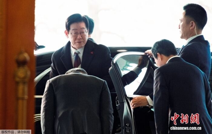 当地时间12月29日零时许，象征韩国国家元首的“凤凰旗”悬挂在青瓦台。当天，韩国总统府正式迁回青瓦台。图为韩国总统李在明(左)抵达青瓦台。