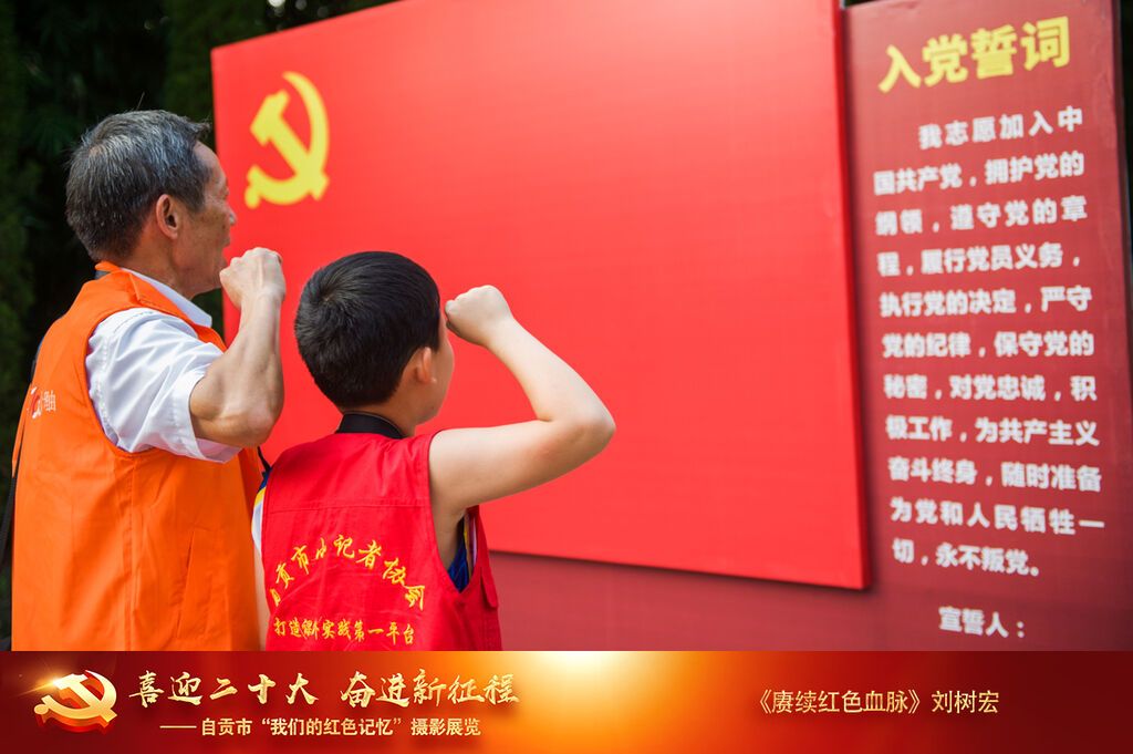 劉樹宏《賡續(xù)紅色血脈》18808224115  2019年9月28日攝于盧德銘故居 爺爺在黨旗下重溫入黨誓言，孫子學(xué)著爺爺?shù)臉幼右睬f嚴(yán)的舉起了右手。.jpg