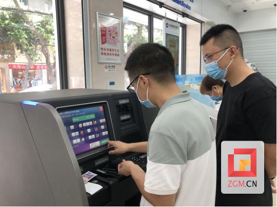 图为：建行工作人员引导客户体验纸硬币自助兑换机