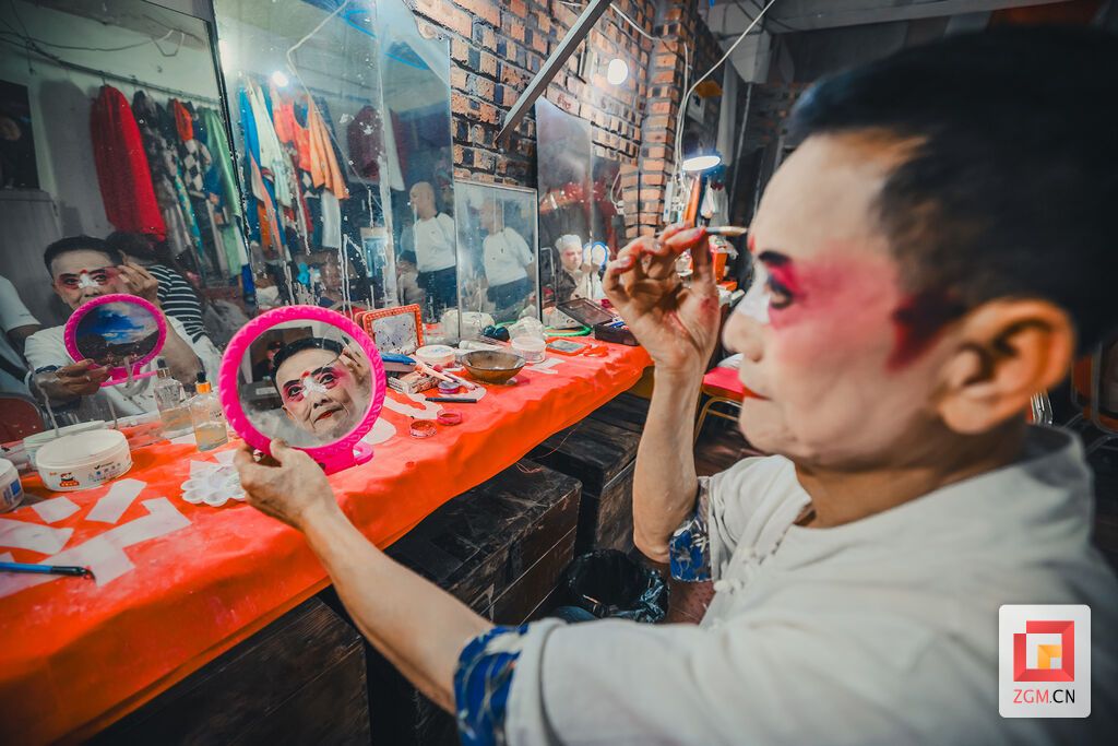 演员正对着一面布满水渍的旧镜子,手握画笔,正精心勾勒脸谱上的线条 记者 宋姿熠 摄.jpg