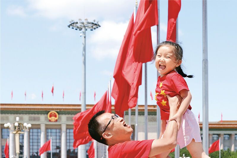 2021年7月3日，不少北京市民和游客来到天安门广场参观游览，感受庆祝中国共产党成立100周年大会的氛围。图为前来参观的家长举起孩子拍照留念。　中新社发 陈晓根/摄
