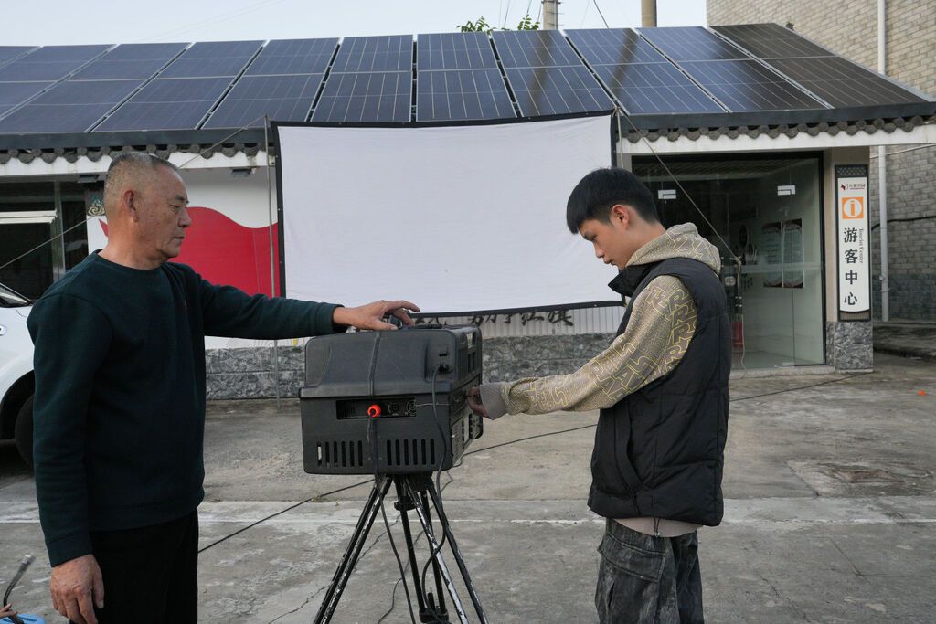 爷爷陶洪正在和孙鼻子一起调试，集投影、音响和片源于一体的便携数字放映机.jpg