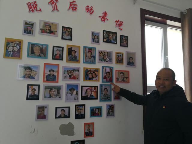 2020年12月11日，来玉村扶贫第一书记李玉栋向记者介绍来玉村“脱贫后的喜悦”。照片墙集纳了村民们脱贫后的笑脸照片。（新华社记者顾玲摄）