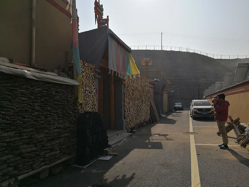 在搬迁下山后的来玉村，25岁的村民才华杰抱着孩子站在家门前（2020年12月11日摄）。新华社记者 顾玲 摄