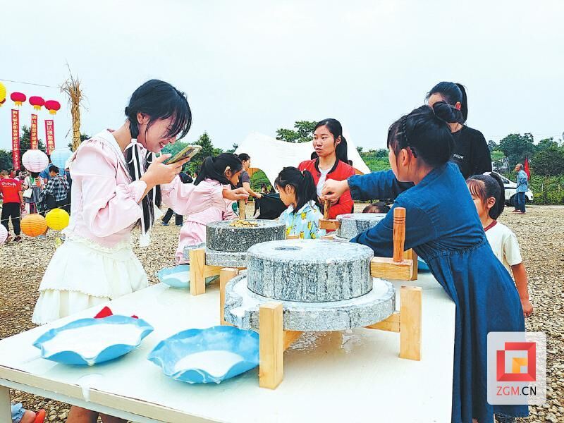 游客在永安镇草雕主题游园活动中体验推磨子