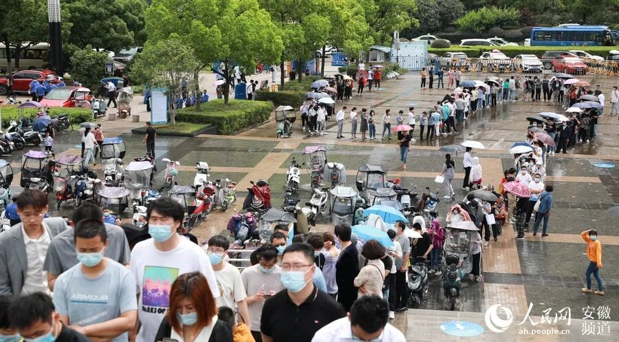 奥体中心方舱式疫苗接种点外，市民正在冒雨排队。人民网 李希蒙摄
