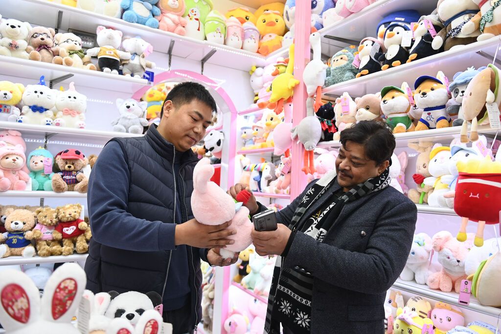 2023年2月2日,来自印度的客商(右)在义乌国际商贸城的一家玩具店铺内选购。